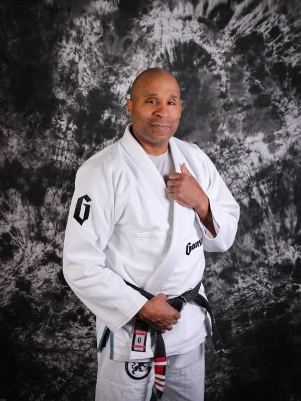 Studio portrait of Professor Gideon "The Gladiator" Ray in a white gi and Brazilian Jiu Jitsu black belt.